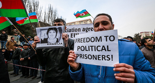 Участник митинга в Баку держит в руках портрета политзаключенных Хадиджа Исмаил и плакат - " Свободу политическим заключенным ". Фото Азиза Каримова для "Кавказского узла"