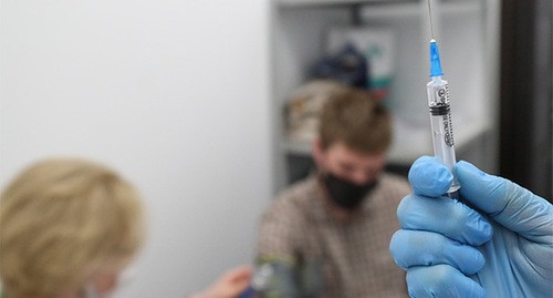 Медицинский работник держит шприц. Фото: REUTERS/Евгения Новоженина