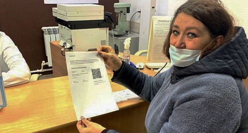 Женщина держит листок с QR-кодом. Скриншот видео "Астрахань24" https://astrakhan-24.ru/