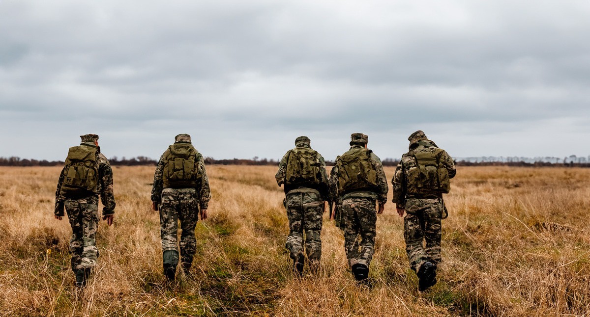 Военные идут по полю. Иллюстрация создана "Кавказским узлом" с помощью ИИ в программе Photoshop